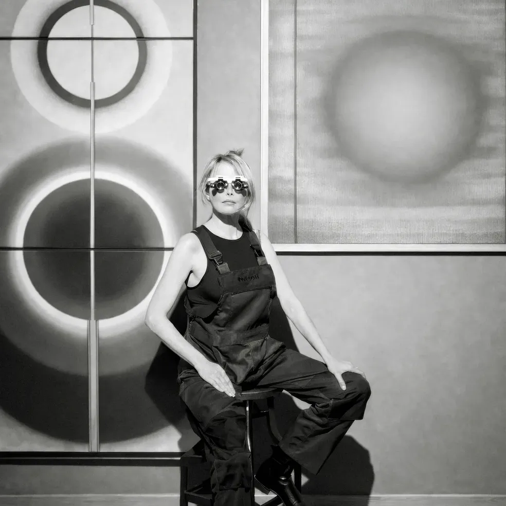 Pi Square artist seated in studio with paintings exploring light, structure, and perception